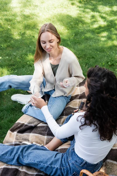 Young lesbian couple holding glasses while sitting on blanket — Stock Photo