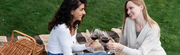 Happy lesbian couple clinking glasses of red wine during picnic, banner — Stock Photo