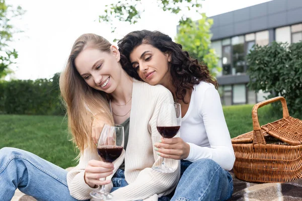 Joven pareja lesbiana sosteniendo vasos de vino tinto afuera - foto de stock