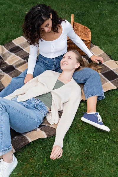 Happy lesbian couple lying on plaid blanket during picnic — Stock Photo