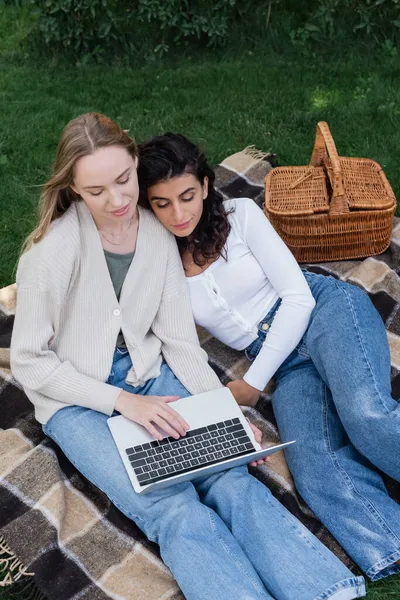 Высокий угол обзора молодых лесбиянок, смотрящих кино на ноутбуке во время пикника — стоковое фото
