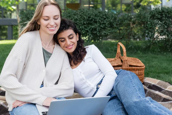 Счастливые женщины смотрят кино на ноутбуке во время пикника — стоковое фото
