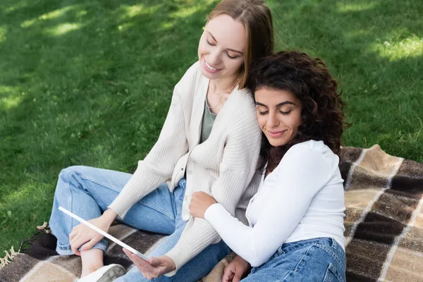 Mulheres lésbicas felizes sentadas com tablet digital durante piquenique — Fotografia de Stock