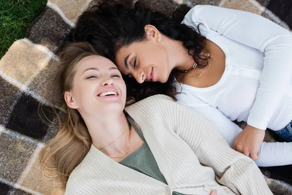 Vue de dessus des femmes joyeuses allongées sur une couverture à carreaux — Photo de stock