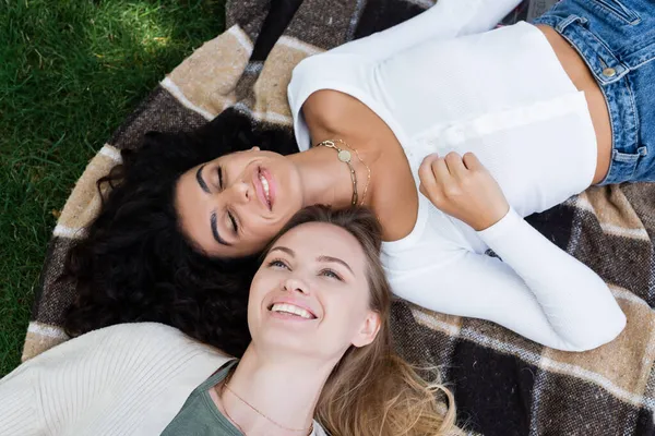 Top view of happy lesbian women lying on checkered blanket — Stock Photo
