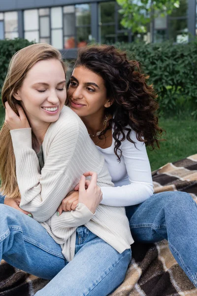 Joyful lesbian women hugging on checkered blanket — Stock Photo