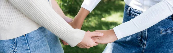 Abgeschnittene Ansicht von Frauen in Jeans, die sich draußen an den Händen halten, Banner — Stockfoto