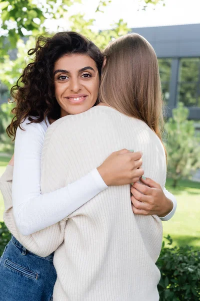 Heureuse bouclée femme étreignant copine à l'extérieur — Photo de stock