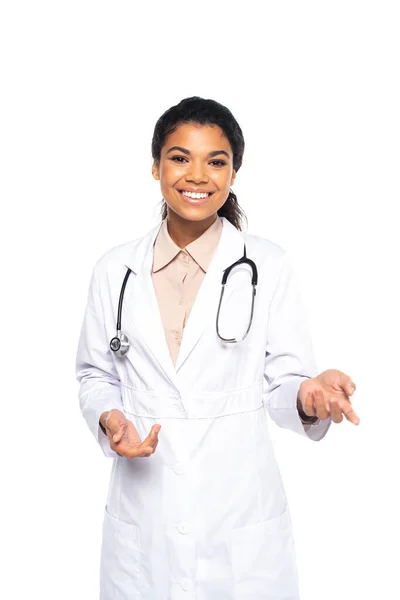 Positive african american doctor in white coat looking at camera isolated on white — Stock Photo