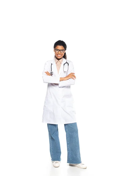 Full length of smiling african american oculist crossing arms on white background — Stock Photo