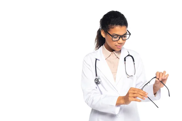 Young african american ophthalmologist looking at eyeglasses isolated on white — Stock Photo