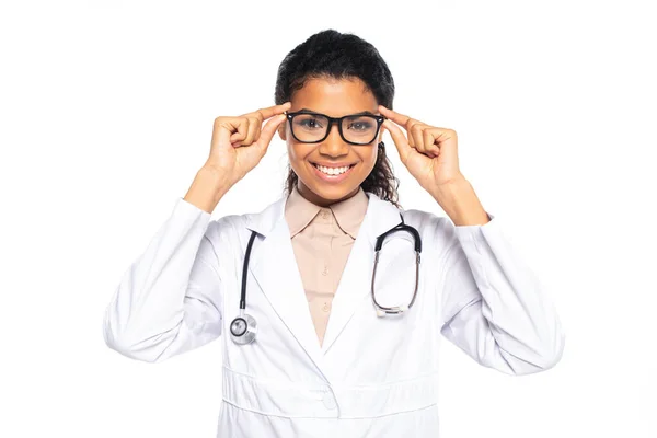 Smiling african american oculist holding eyeglasses isolated on white — Stock Photo