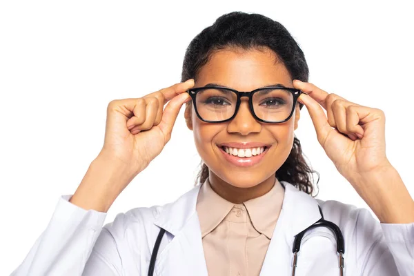 Alegre oculista afroamericano en bata blanca y anteojos aislados en blanco - foto de stock