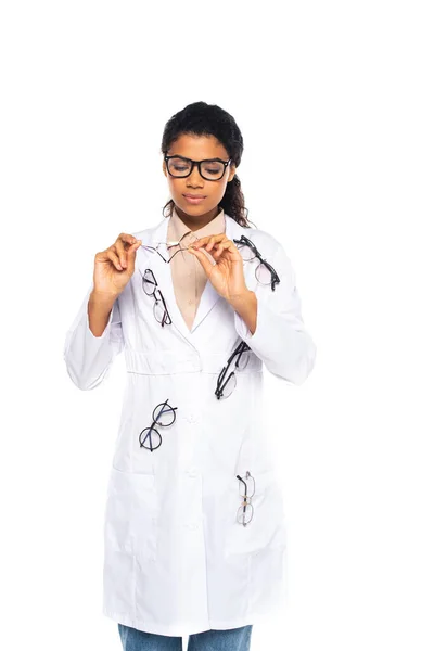Ziemlich afrikanisch-amerikanischer Augenarzt im Mantel schaut auf eine Brille isoliert auf weißem Grund — Stockfoto