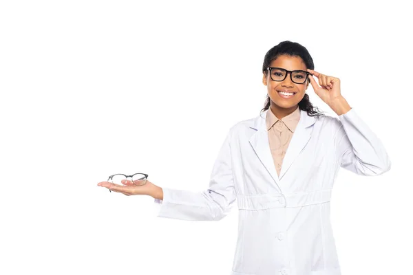 Oftalmólogo afroamericano ajustando gafas aisladas en blanco - foto de stock