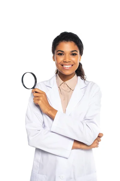 African american ophthalmologist holding magnifying glass and looking at camera isolated on white — Stock Photo