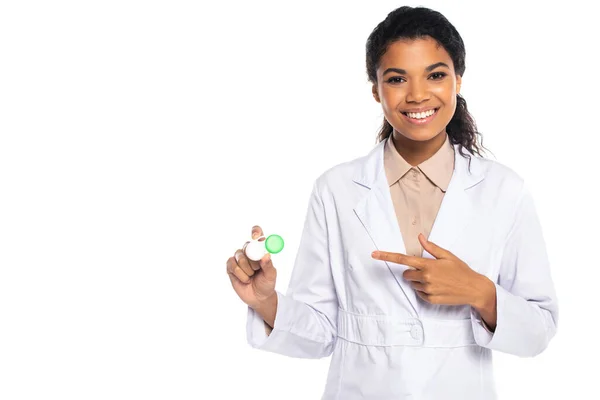 Jeune ophtalmologiste afro-américain pointant vers le récipient avec des lentilles de contact isolées sur blanc — Photo de stock