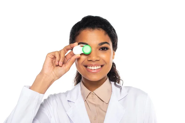 Sorridente medico afroamericano che tiene le lenti a contatto vicino al viso isolato su bianco — Foto stock