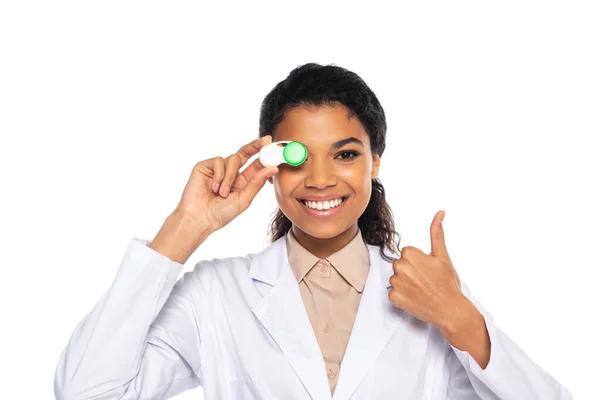 Sorrindo afro-americano oculista mostrando como e segurando recipiente com lentes de contato isolado no branco — Fotografia de Stock