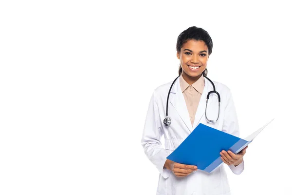 Oculista afroamericano sonriente sosteniendo carpeta de papel aislado en blanco - foto de stock