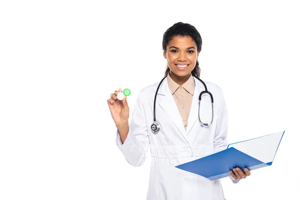 Heureux médecin afro-américain tenant conteneur avec lentilles de contact et dossier en papier isolé sur blanc — Photo de stock