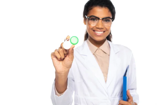 Container with contact lenses in hand of blurred african american oculist with paper folder isolated on white — Stock Photo