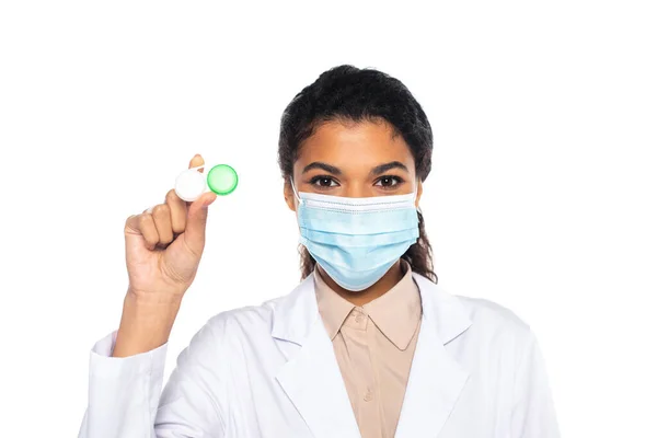 Médecin afro-américain en masque médical tenant des lentilles de contact isolées sur blanc — Photo de stock