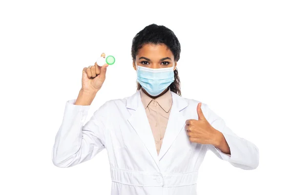 African american doctor in medical mask holding contact lenses and showing like isolated on white — Stock Photo