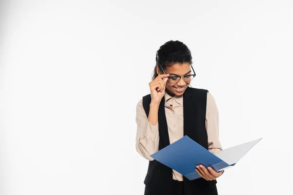 Happy african american businesswoman holding eyeglasses and paper folder isolated on white — Stock Photo