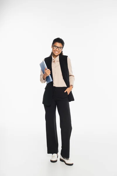 Cheerful african american businesswoman holding paper folder and looking at camera on white background — Stock Photo