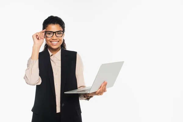 Sorrindo afro-americana empresária em óculos segurando laptop isolado em branco — Fotografia de Stock