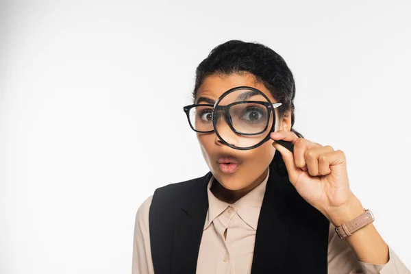 Amazed african american businesswoman holding magnifying glass on white — Stock Photo