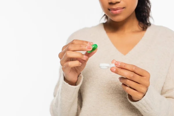 Vista recortada de mujer afroamericana sosteniendo contenedor con lentes de contacto aisladas en blanco - foto de stock