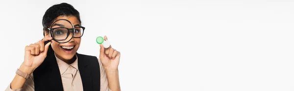 Empresária americana africana alegre segurando lupa e lentes de contato isoladas em branco, banner — Fotografia de Stock