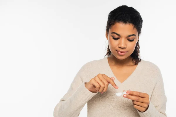 Joven mujer afroamericana sosteniendo lentes de contacto en contenedor aislado en blanco - foto de stock