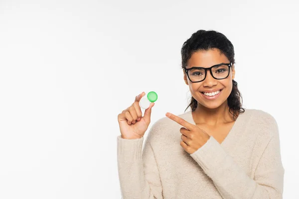 Smiling african american woman in eyeglasses pointing at contact lenses isolated on white — Stock Photo