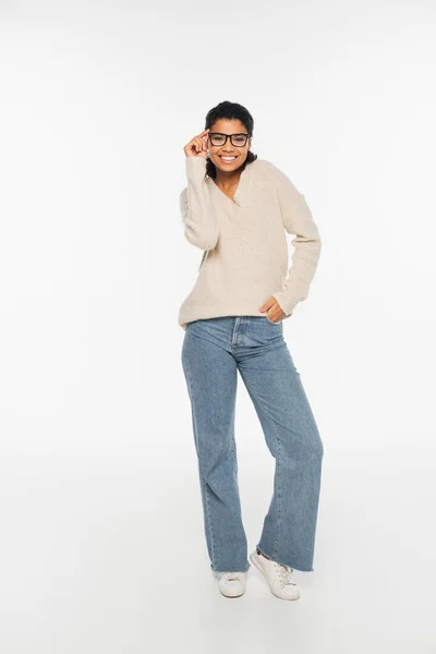 Full length of smiling african american woman in eyeglasses looking at camera on white background — Stock Photo