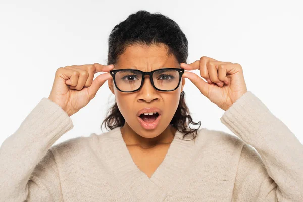 Mujer afroamericana confusa en anteojos mirando a cámara aislada en blanco - foto de stock