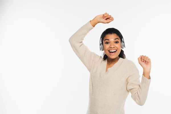 Mujer afroamericana positiva usando auriculares aislados en blanco - foto de stock