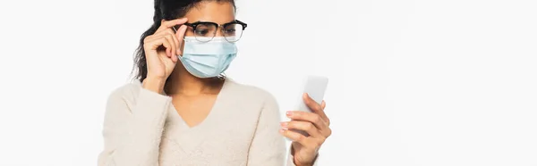 African american woman in eyeglasses and medical mask using cellphone isolated on white, banner — Stock Photo