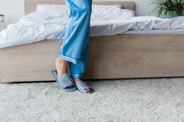 Cropped view of african american woman in pajamas and slippers standing near bed — Stock Photo