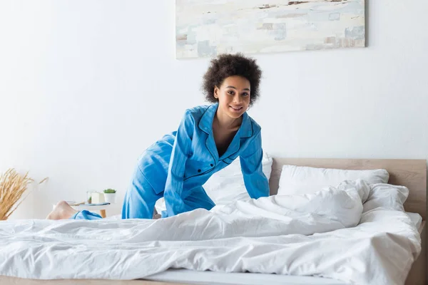 Joyeuse jeune femme afro-américaine en pyjama sur le lit — Photo de stock