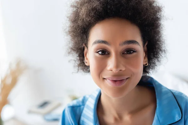 Sonriente mujer afroamericana en pijama azul mirando a la cámara - foto de stock