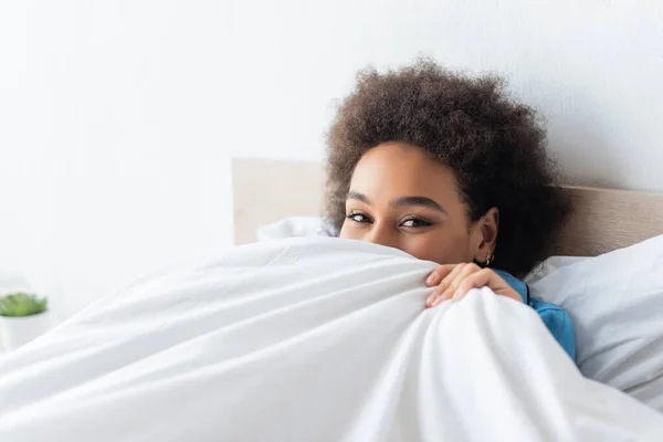 Rizado africano americano mujer cubriendo la cara con manta - foto de stock