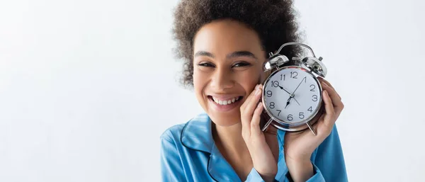 Positive african american woman in pajamas holding alarm clock, banner — Stock Photo