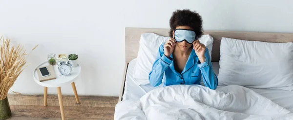 Vue grand angle de la femme afro-américaine ajustement masque de couchage dans la chambre, bannière — Photo de stock