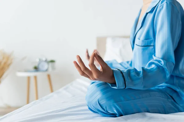 Cropped view of african american woman in pajamas meditating on bed — Stock Photo