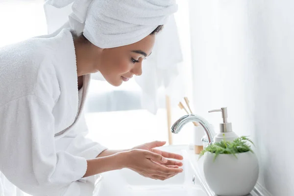 Jeune femme afro-américaine se laver les mains dans la salle de bain — Photo de stock