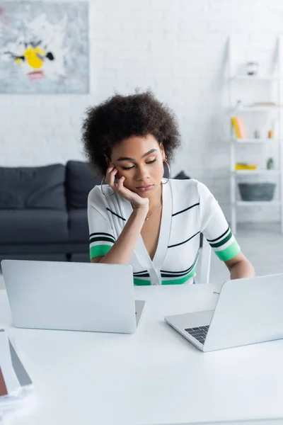 Bored african american freelancer working from home near laptops on desk — Stock Photo