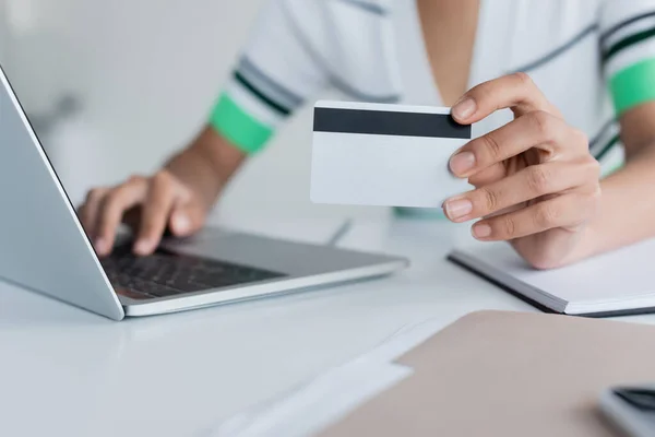 Vue recadrée de femme afro-américaine tenant une carte de crédit et utilisant un ordinateur portable — Photo de stock